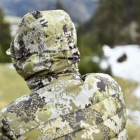 blaser-herren-daunenjacke-observer.. Die Blaser Herren Daunenjacke Oberserver in Huntec Camo ist wasserabweisend.Sie verfügt über 2 Seitentaschen. Bild mit verschwommenem Wiesenhintergrund.