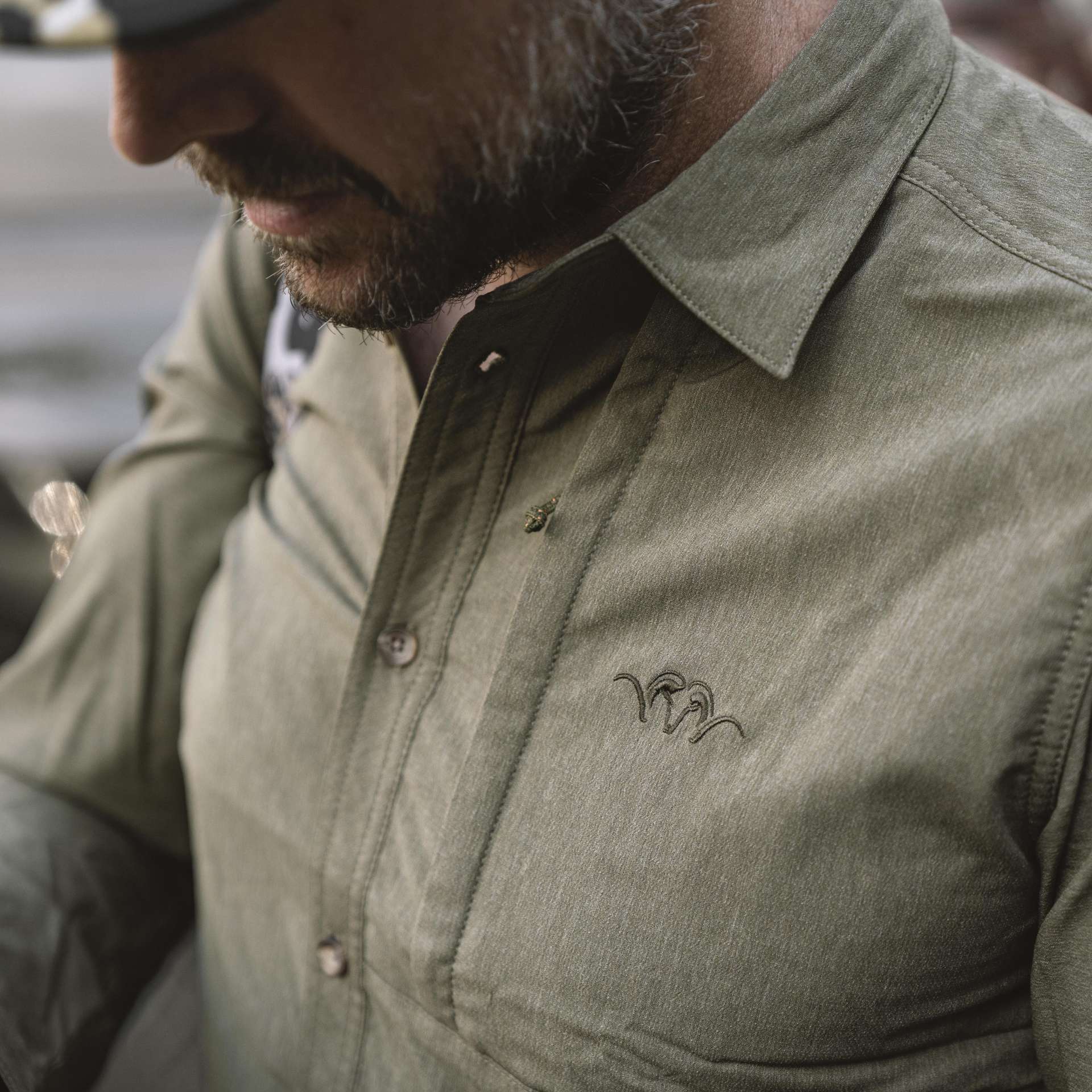 Das Blaser Herren Jagdhemd AirFlow in dunklen oliv verfügt ist schnelltrocknend und hoch atmungsaktiv durch den doppelt gewebten Stoff. Button-Down-Kragen und Brusttasche mit Argali-Logo. Bild auf weißem Hintergrund.